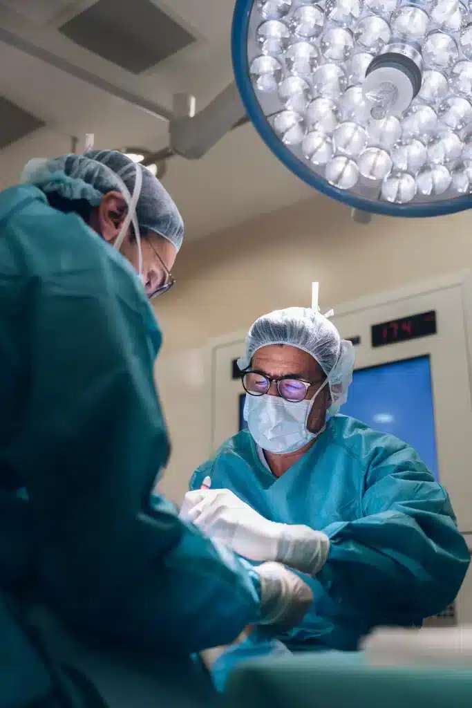 cirujanos-urologicos-merida-en-quirurgico-moderno Cirujanos realizando operación urológica en hospital de Mérida, bajo equipo profesional y luz quirúrgica.