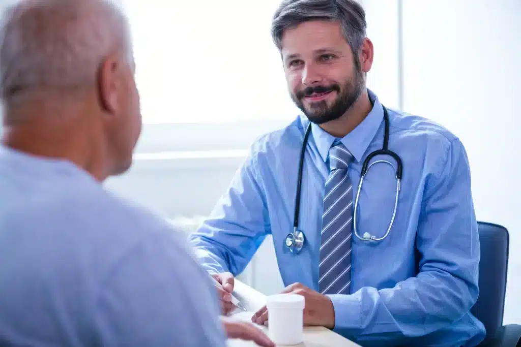 consulta-urologica-hombres-merida-enfoque-cercano Médico sonriente conversando con un paciente mayor durante una consulta urológica para hombres en Mérida, con un trato cercano y humano.