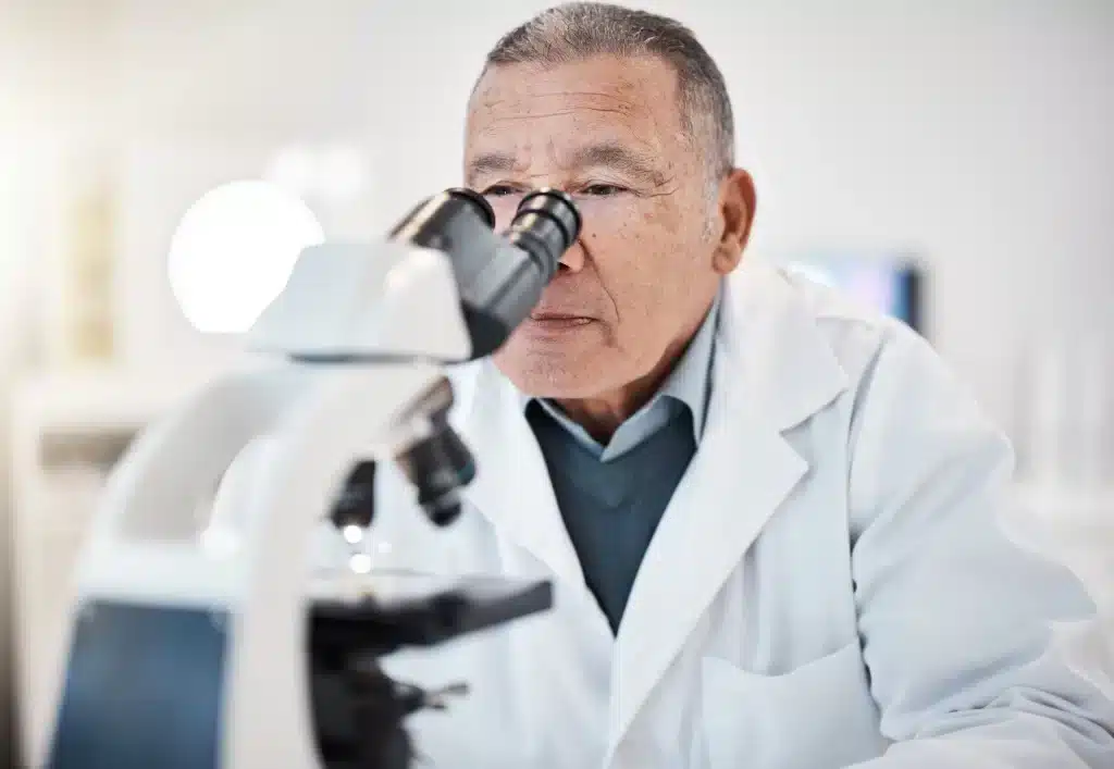 estudio-urologico-particular-en-merida-con-analisis-microscopico Especialista senior observando una muestra en microscopio durante estudio urológico en Mérida.